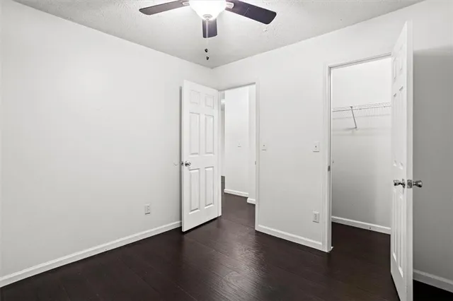 an empty room with wooden floor and ceiling fan