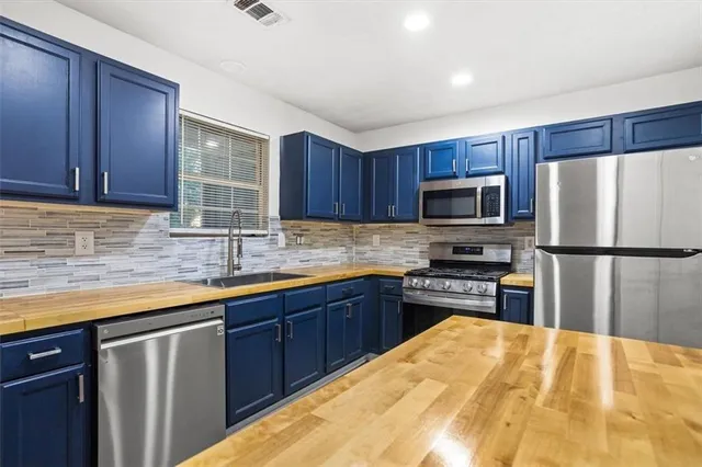 a kitchen with stainless steel appliances granite countertop a sink stove microwave and refrigerator