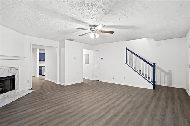 a view of an empty room with wooden floor fireplace and a chandelier fan