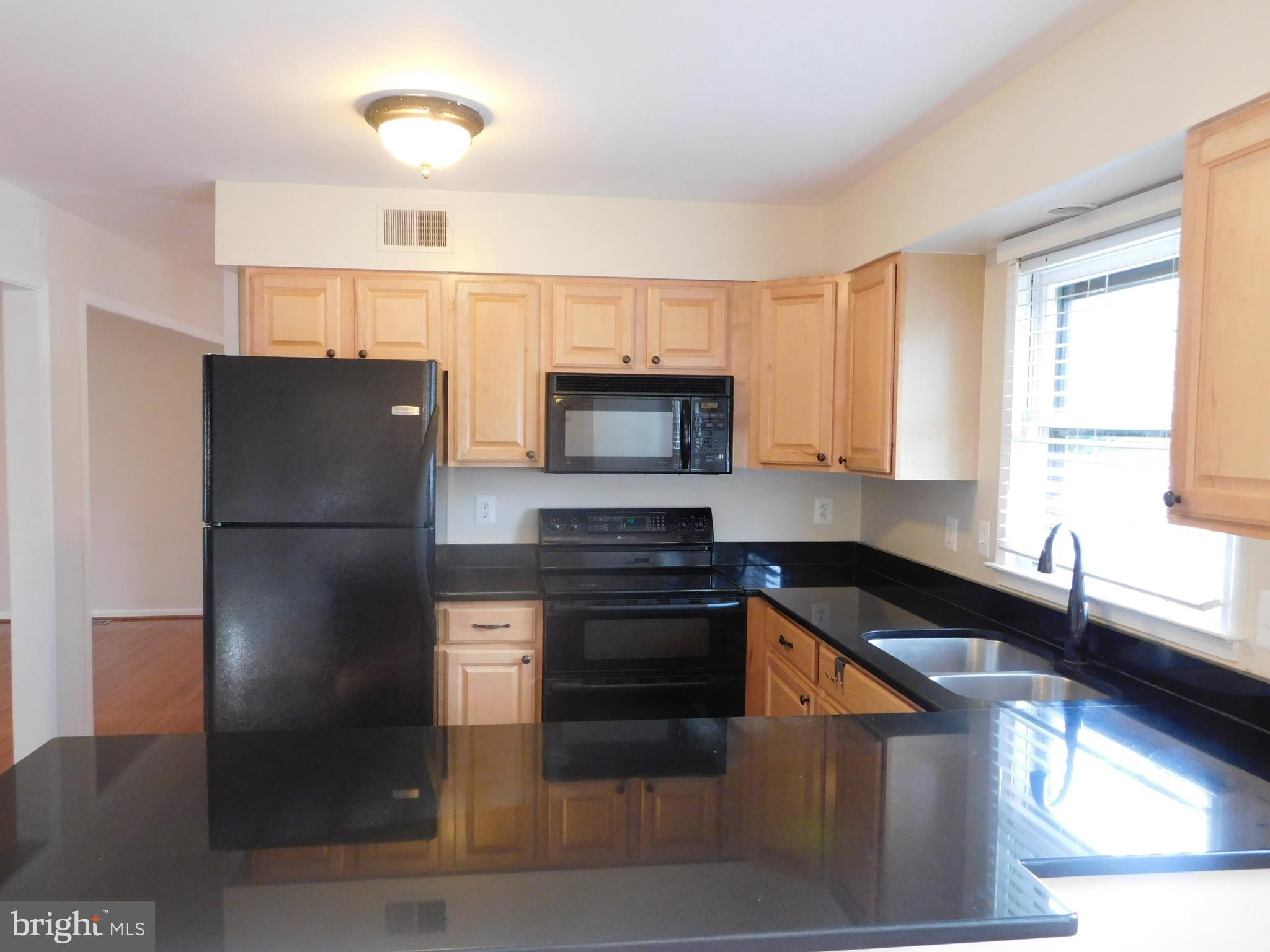 9239 Rockefeller Lane Springfield, VA 22153 - Photo 7 of 20 a kitchen with granite countertop a refrigerator stove and microwave
