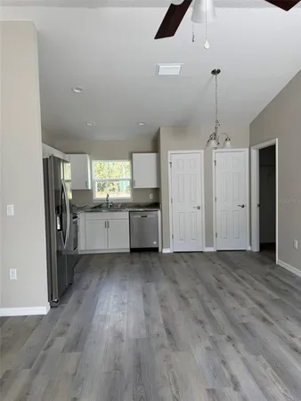 an empty room with wooden floor and a kitchen