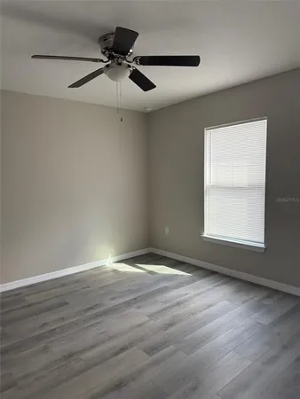 a view of an empty room with wooden floor and a window