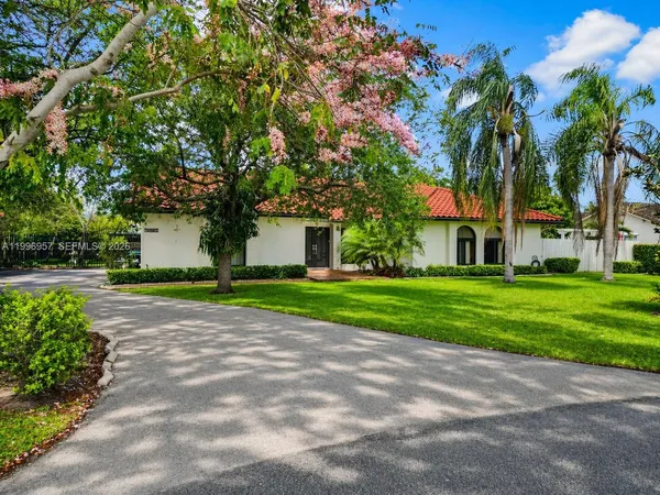 a front view of a house with a yard and potted plants