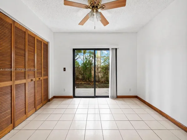 an empty room with chandelier fan and windows