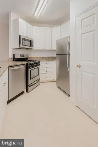 a kitchen with granite countertop white cabinets and stainless steel appliances