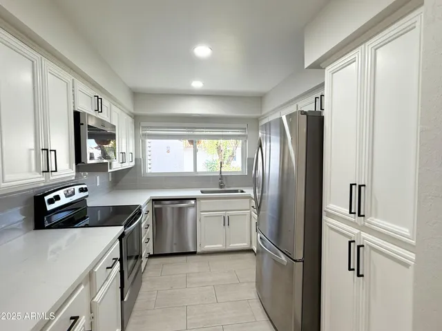 a kitchen with stainless steel appliances granite countertop a refrigerator a sink a stove and a refrigerator with wooden cabinets