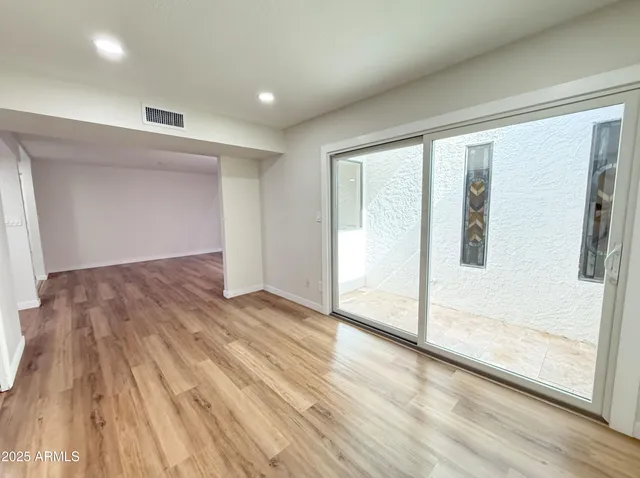 a view of empty room with wooden floor and fan
