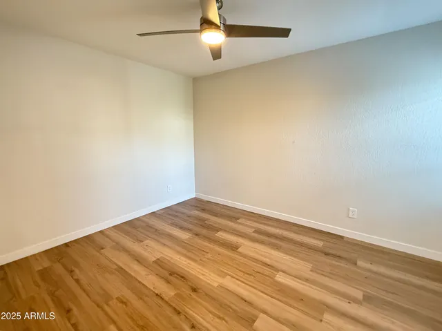 an empty room with wooden floor and fan