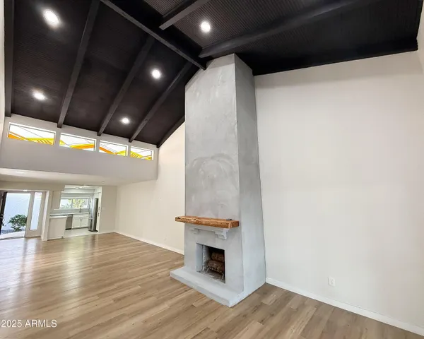 a view of an empty room with wooden floor and fire place