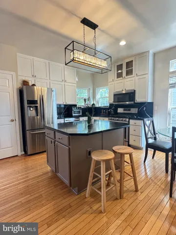 a kitchen with stainless steel appliances a dining table chairs stove refrigerator and cabinets