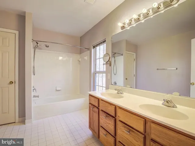 a bathroom with a tub sink double vanity and shower