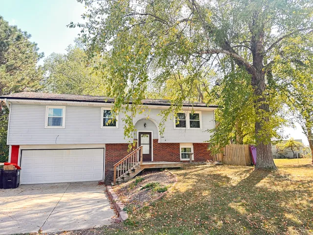 a view of a house with a large tree and a yard