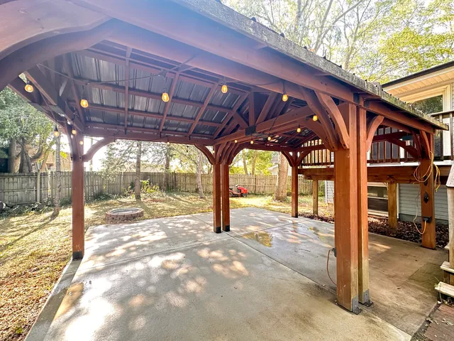 a view of a backyard with wooden fence and large trees