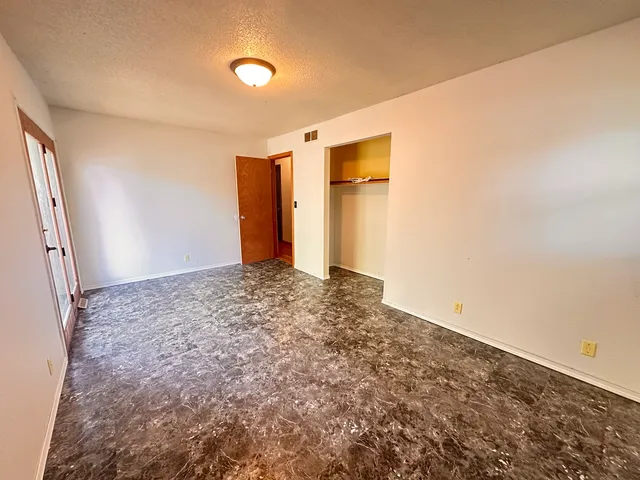 an empty room with windows and fan