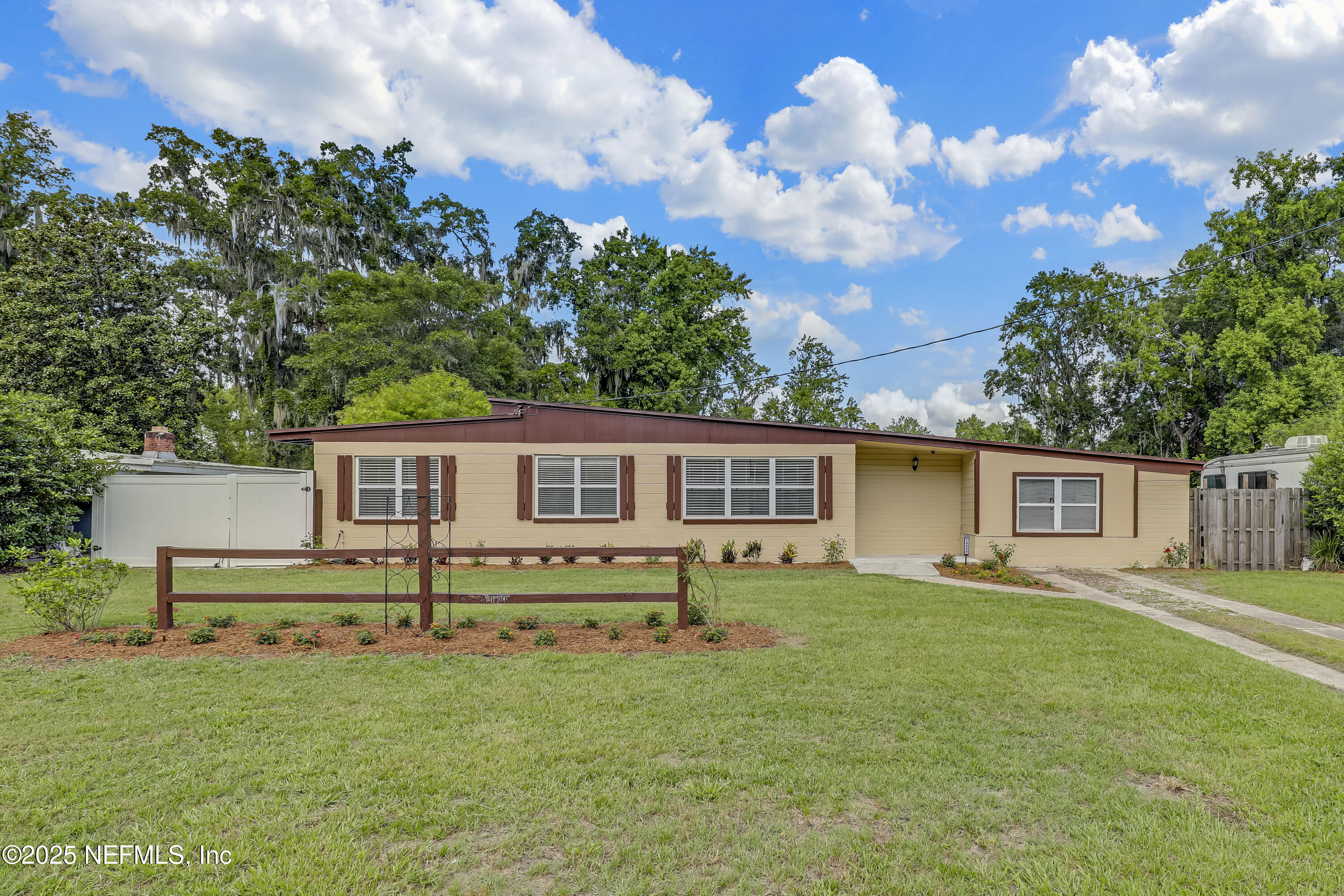 a front view of house with yard and trees in the background
