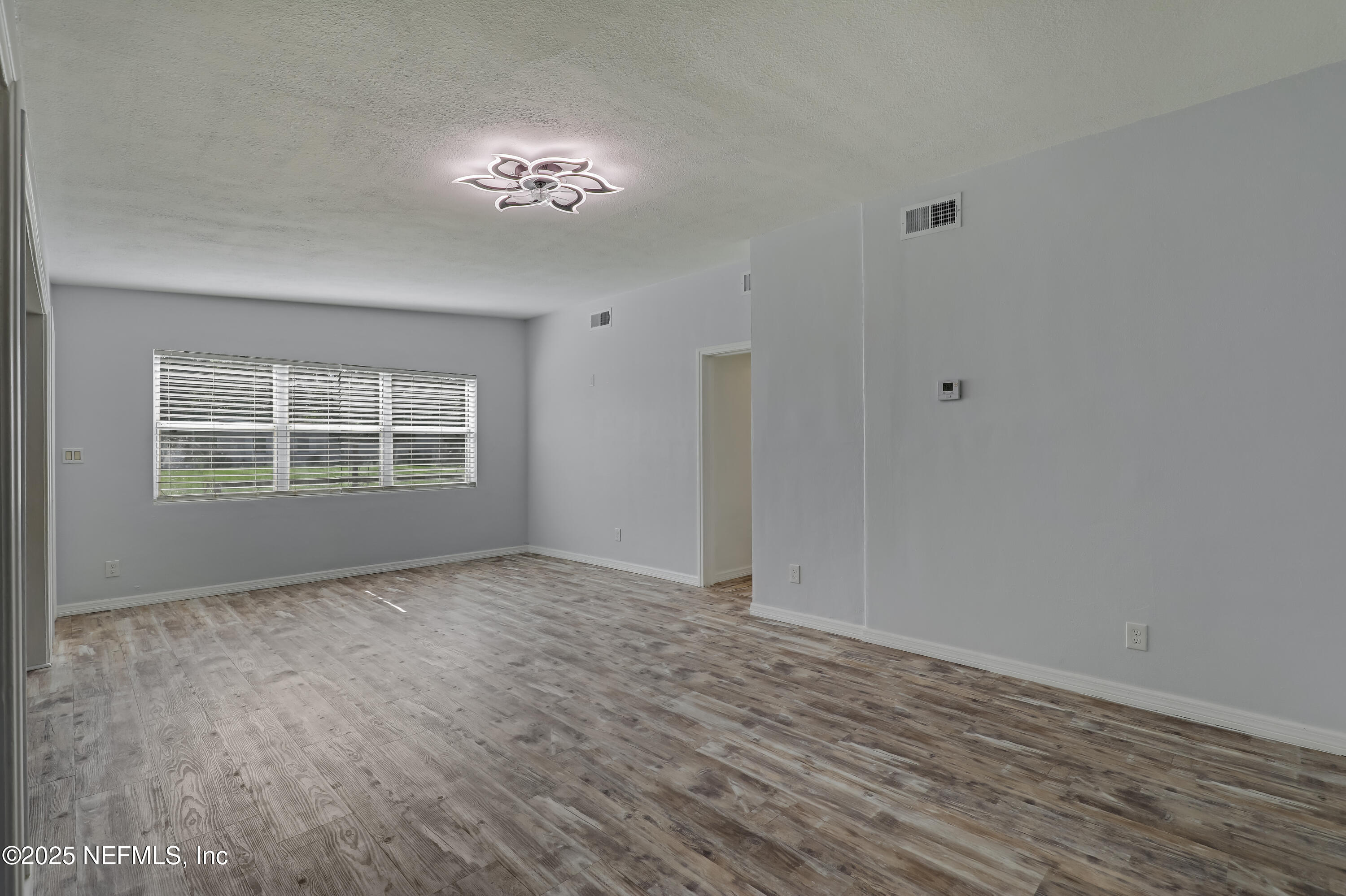 10524 Rutgers Road Jacksonville, FL 32218 - Photo 11 of 46 a view of an empty room with wooden floor and a window