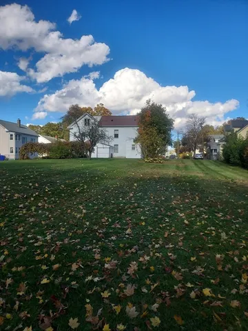 a view of a white house with a big yard and large trees
