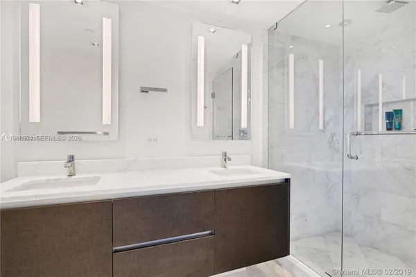a bathroom with a double vanity sink a mirror and a bathtub