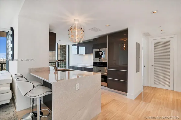 a kitchen with stainless steel appliances kitchen island granite countertop a table chairs in it and wooden floors