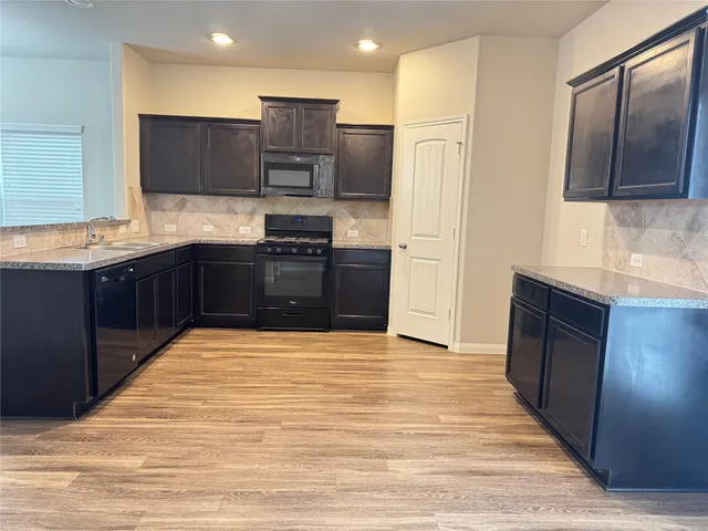 a large kitchen with stainless steel appliances granite countertop a refrigerator and a sink