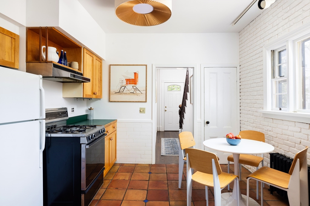 9 Carver Street Somerville, MA 02143 - Photo 5 of 11 a kitchen with stainless steel appliances granite countertop a stove a refrigerator a dining table and chairs with wooden floor