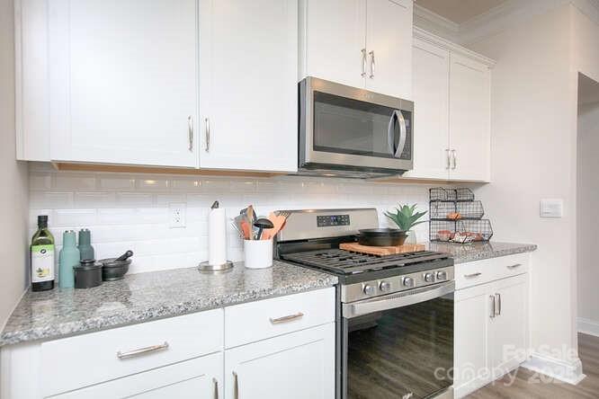 4245 Millstream Road Denver, NC 28037 - Photo 7 of 47 a kitchen with granite countertop a stove a sink and a white cabinets