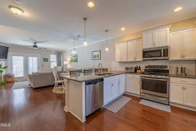 a large kitchen with stainless steel appliances granite countertop a stove and a wooden floors