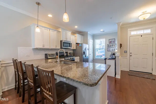 a kitchen with kitchen island granite countertop a table chairs sink and microwave