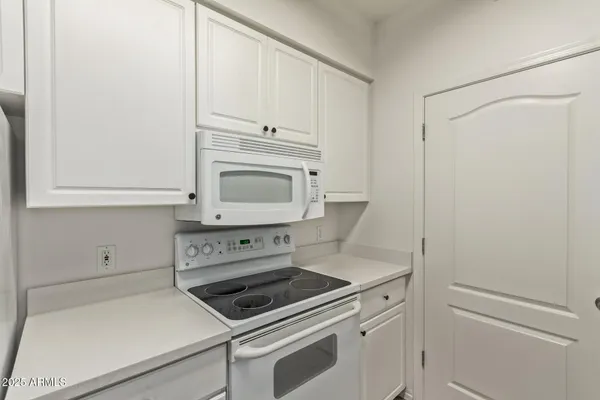 a kitchen with white cabinets and white appliances