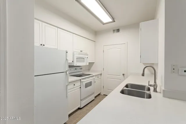 a kitchen with white cabinets and white appliances
