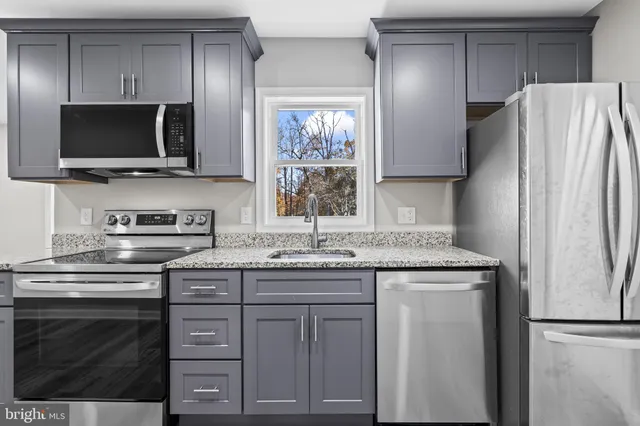 a kitchen with stainless steel appliances granite countertop a refrigerator and a stove top oven
