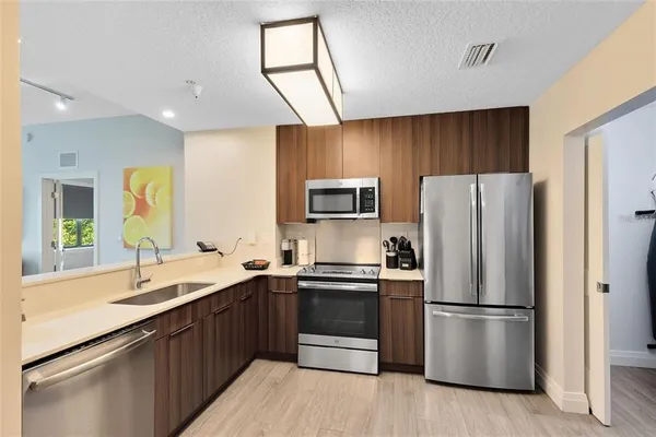 a kitchen with a refrigerator a sink stainless steel appliances cabinets and a counter top space