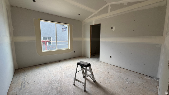 1862 Mantle Way, Unit 418 Tooele, UT 84074 - Photo 6 of 10 Unfinished interior room featuring a large window, a partial vaulted ceiling, and an open doorway