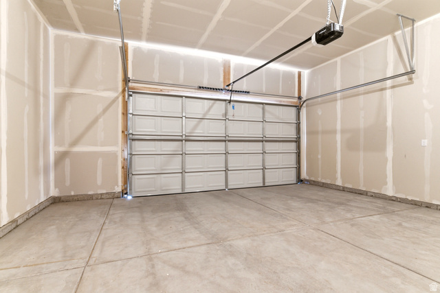 7243 West Terraine Road West Jordan, UT 84081 - Photo 29 of 31 Spacious garage featuring a paneled overhead door, concrete flooring, automatic opener mechanism, and unfinished drywall walls