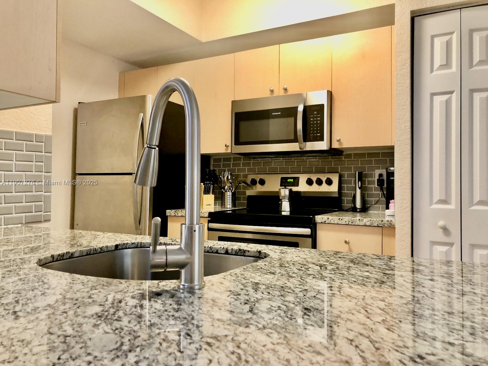 2532 Centergate Drive, Unit 102 Miramar, FL 33025 - Photo 13 of 58 a kitchen with stainless steel appliances granite countertop a refrigerator a stove and a sink with wooden floor