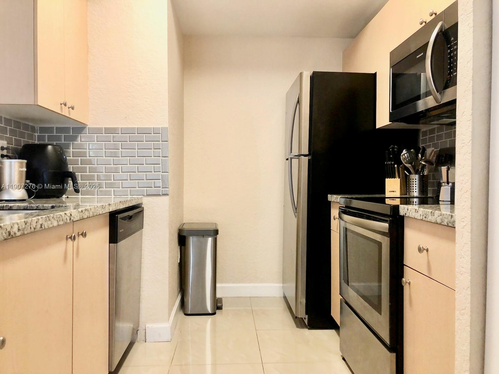2532 Centergate Drive, Unit 102 Miramar, FL 33025 - Photo 17 of 58 a kitchen with stainless steel appliances granite countertop a refrigerator and a stove