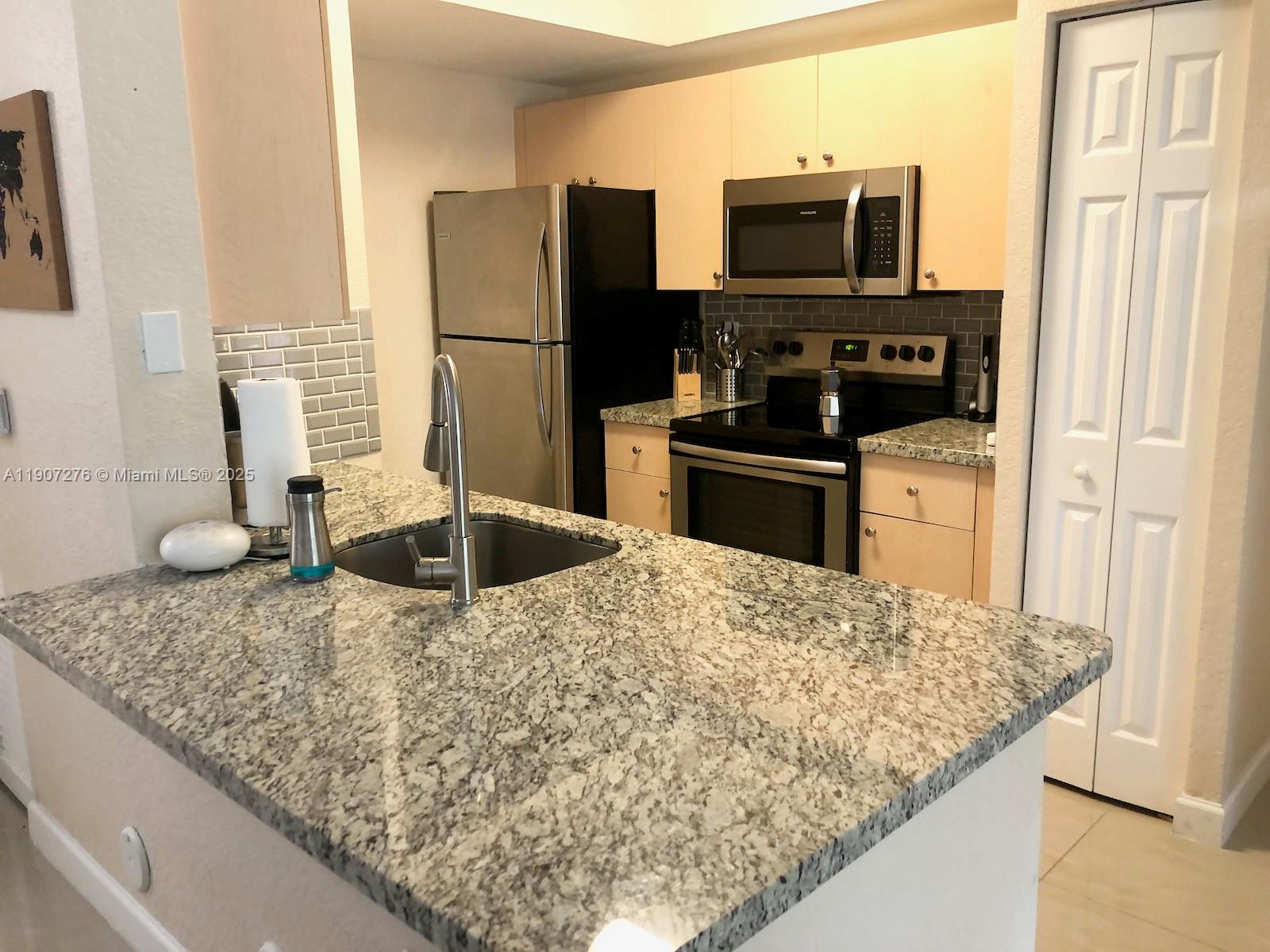 2532 Centergate Drive, Unit 102 Miramar, FL 33025 - Photo 6 of 58 a kitchen with kitchen island granite countertop a sink stove and refrigerator