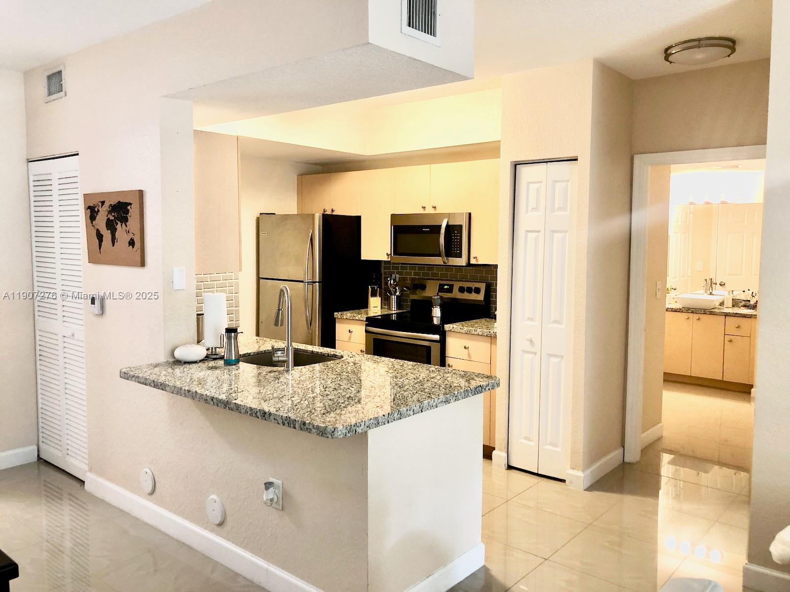 2532 Centergate Drive, Unit 102 Miramar, FL 33025 - Photo 7 of 58 a kitchen with kitchen island granite countertop a sink and refrigerator