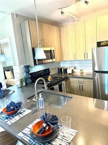 a kitchen with stainless steel appliances granite countertop a sink a stove and a wooden floors