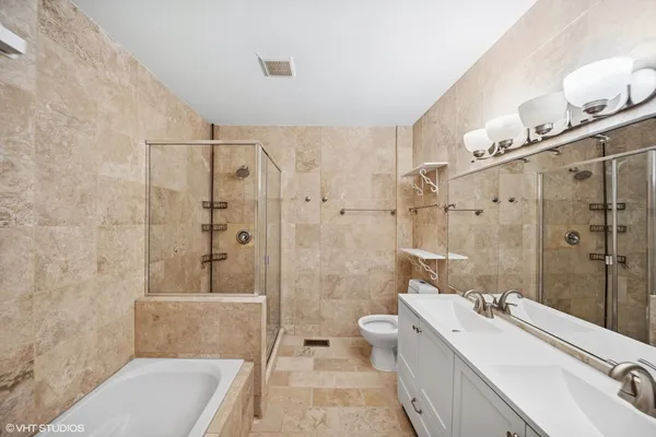 a bathroom with a double vanity sink toilet mirror and shower