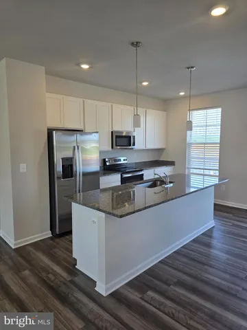 a kitchen with stainless steel appliances granite countertop a refrigerator a stove a sink and a microwave