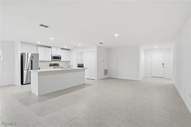 a large white kitchen with white cabinets and stainless steel appliances