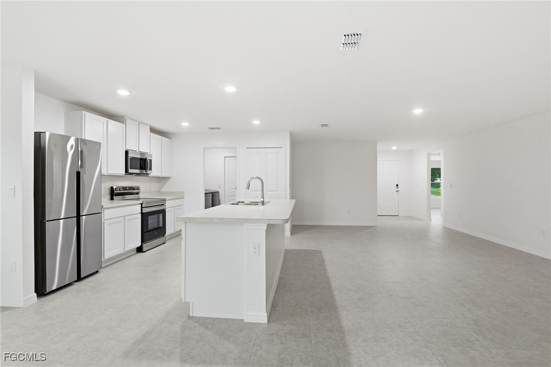 3418 20th Street Southwest Lehigh Acres, FL 33976 - Photo 7 of 34 a kitchen with white cabinets and stainless steel appliances