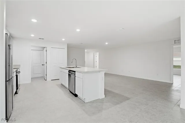 an empty room with a kitchen and windows