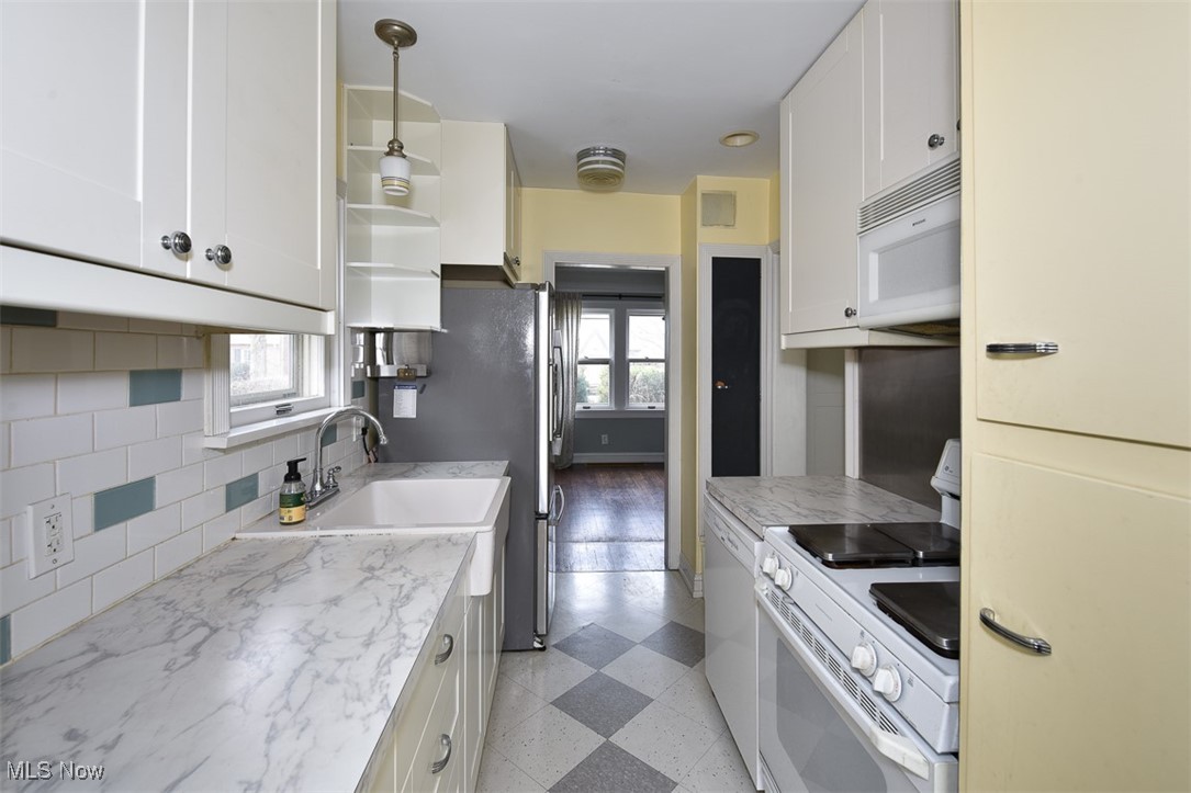 999 Pennfield Road Cleveland, OH 44121 - Photo 12 of 42 Kitchen with white appliances, white cabinetry, tasteful backsplash, light stone countertops, and decorative light fixtures