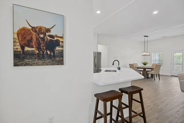 a large white kitchen with stainless steel appliances granite countertop a stove a sink dishwasher and white cabinets with wooden floor