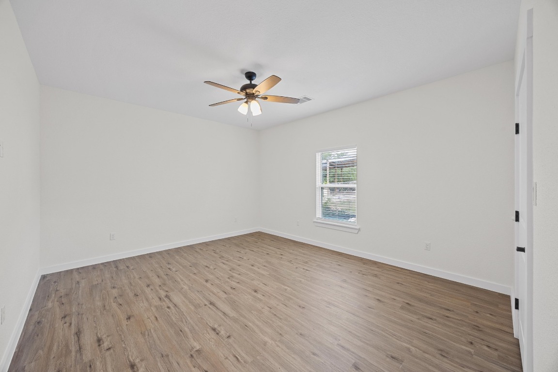 17701 Village Drive Dripping Springs, TX 78620 - Photo 27 of 36 an empty room with wooden floor chandelier fan and windows