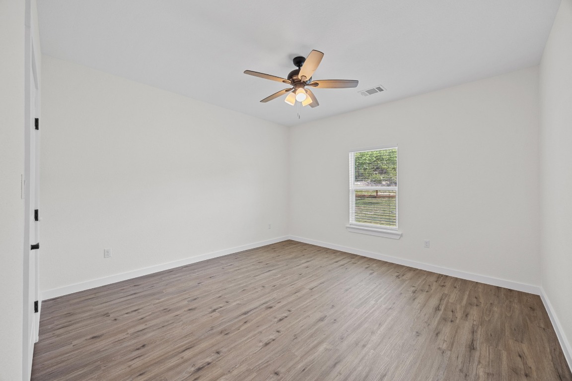 17701 Village Drive Dripping Springs, TX 78620 - Photo 29 of 36 an empty room with wooden floor a ceiling fan and closet