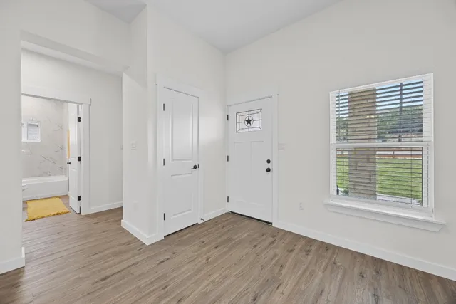 a view of an empty room with wooden floor and a window