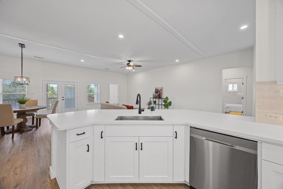 17701 Village Drive Dripping Springs, TX 78620 - Photo 10 of 36 a kitchen with a sink dishwasher and white cabinets with wooden floor